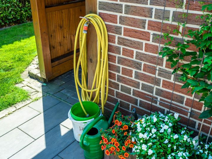 A garden yellow hose connected to a tap protruding from a farm building