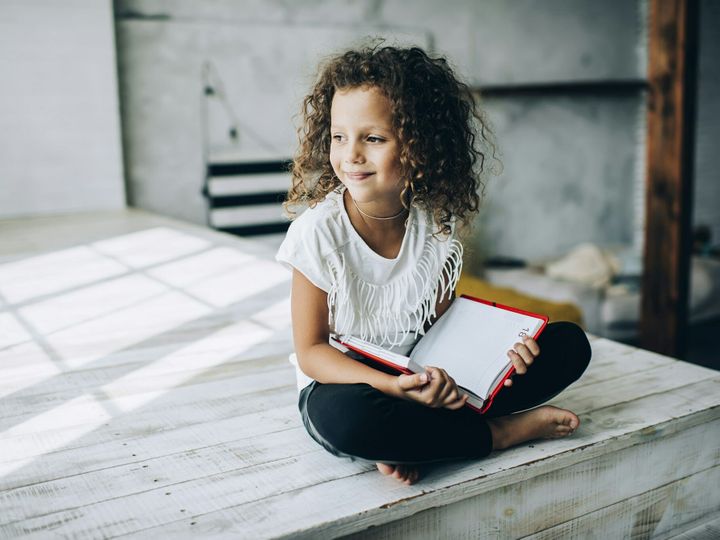 Smiling kid reading book in studio