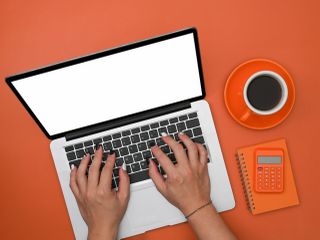 Man using laptop computer on orange background.