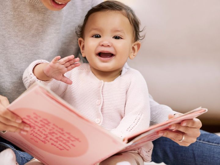 A babys laugh is like an angels voice. Shot a mother reading a book to her baby at home.