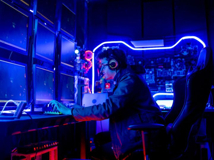 Side view and wide shot of gamer man wear headphone and play game in front of mulimonitor