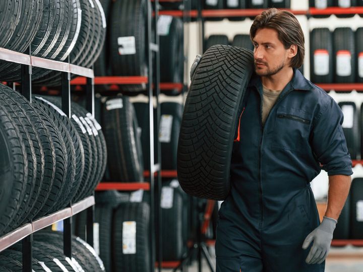 Moving the tire. Man is in the tire fitting car service