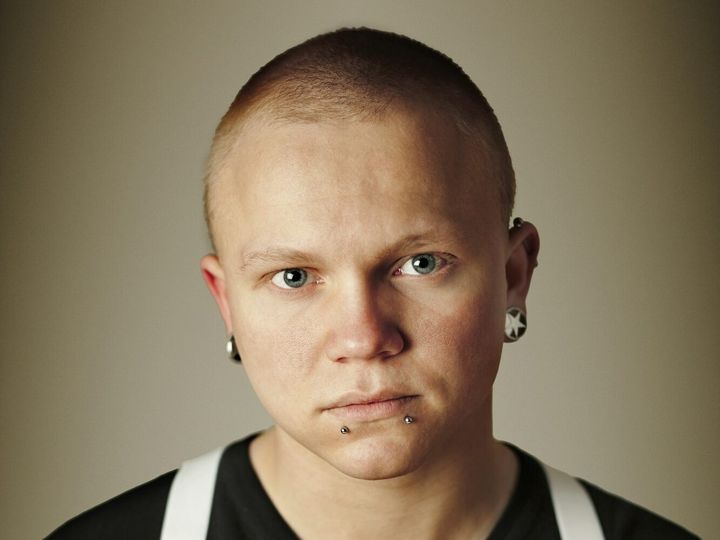 Portrait of young man with piercing standing against wall