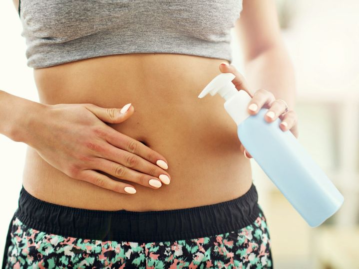 Woman using body lotion on her belly