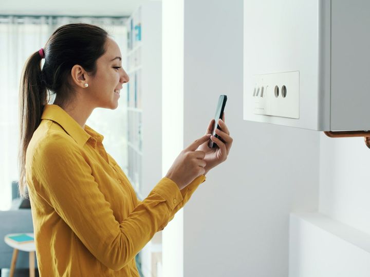 Woman managing her smart boiler using her phone