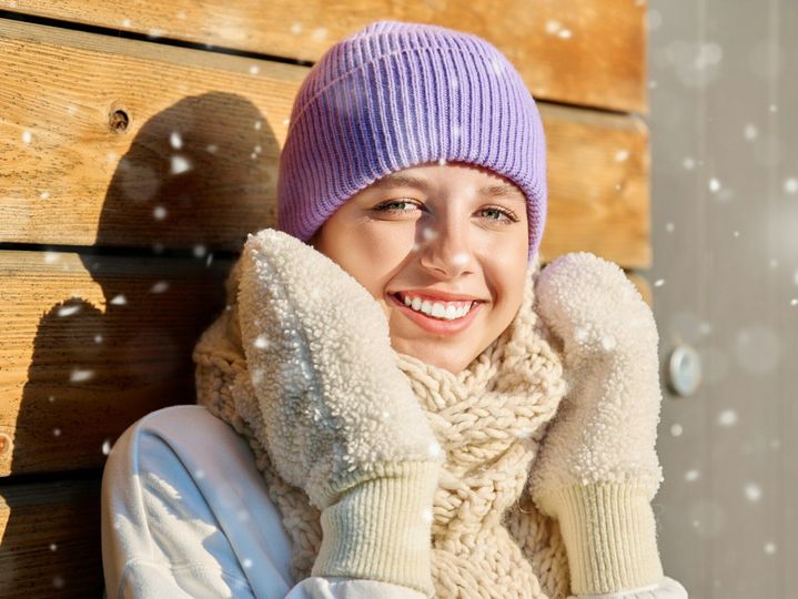 Winter portrait of young woman looking at camera with snowflakes on face