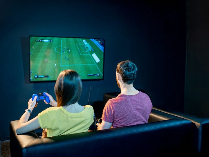 Couple playing football game with gaming console