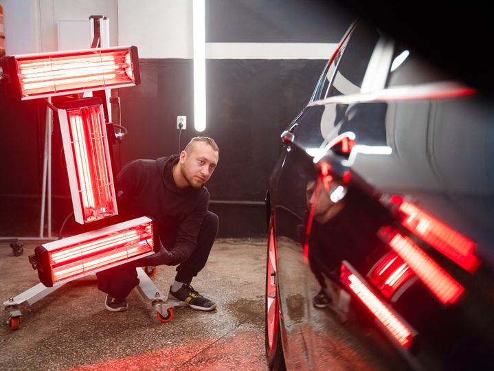 Detailing worker with infrared lamps near the car. Car detailing concept