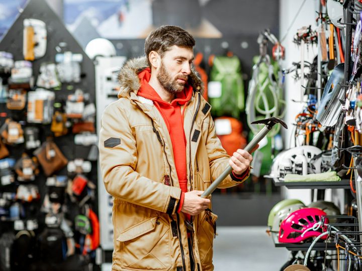 Man choosing choosing mountaineer equipment in the shop