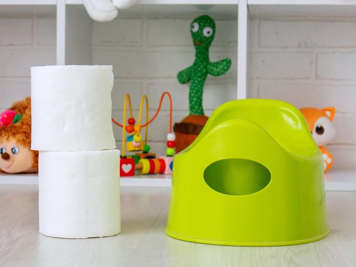 Green potty and toilet paper in the room.