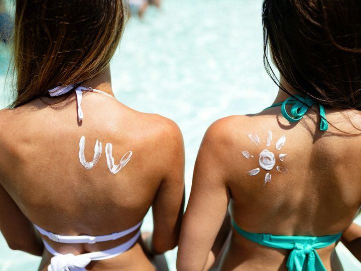 Attractive woman with healthy skin applying sunscreen for healthy tanning