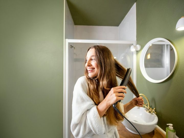 Woman straightening hair in the bathroom