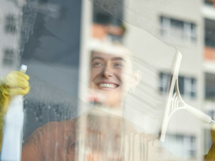 Window cleaning, smile and happy woman at home washing windows with glass cleaner. Helping, working