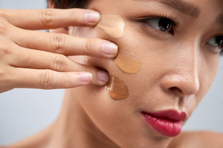 Woman applying foundation on face