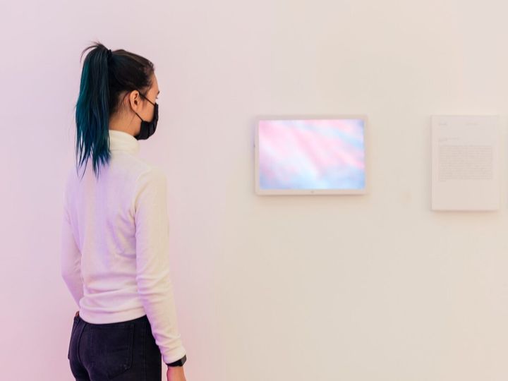 Girl looking at digital frames on a white gallery wall