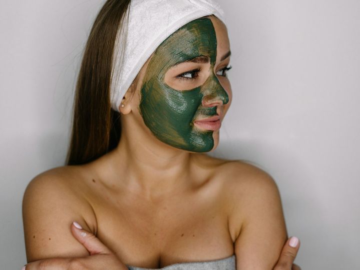 Macro close up portrait of woman having facial cosmetic green algae treatment in spa.