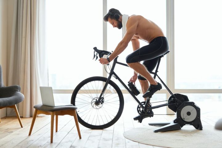 Athletic young man listening to music and riding stationery bike