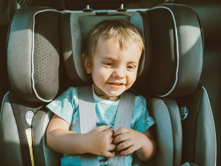 cheerful child boy sitting in a car seat in automobile and smiles