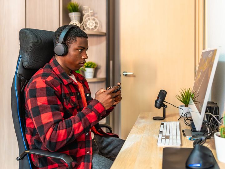 Focused gamer playing video games with headset and controller at home