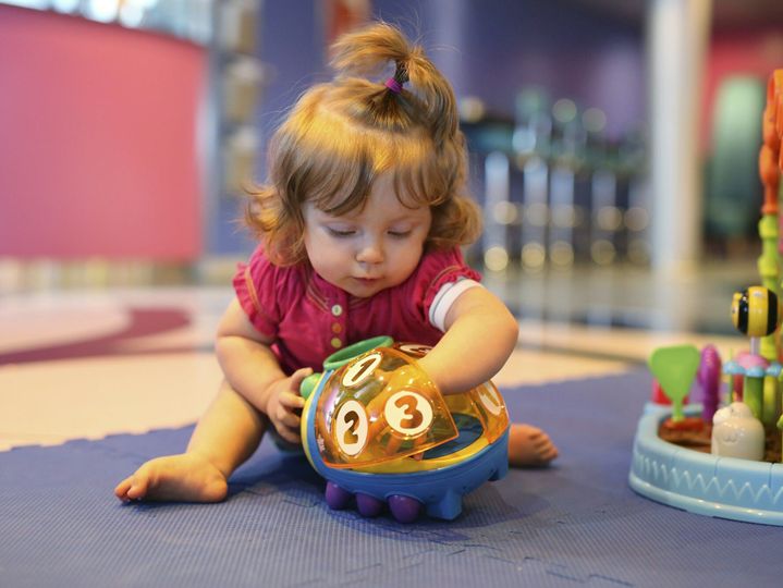 Baby girl playing with toys in a playroom of cruise liner