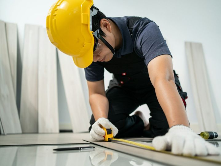 Asian Craftsman worker man use tape measure parquet on corridor to install laminate board on floor