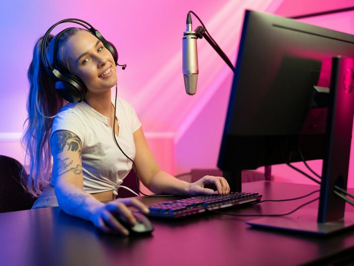 Smiling e-sport gamer girl vlogging and plays online video game on PC